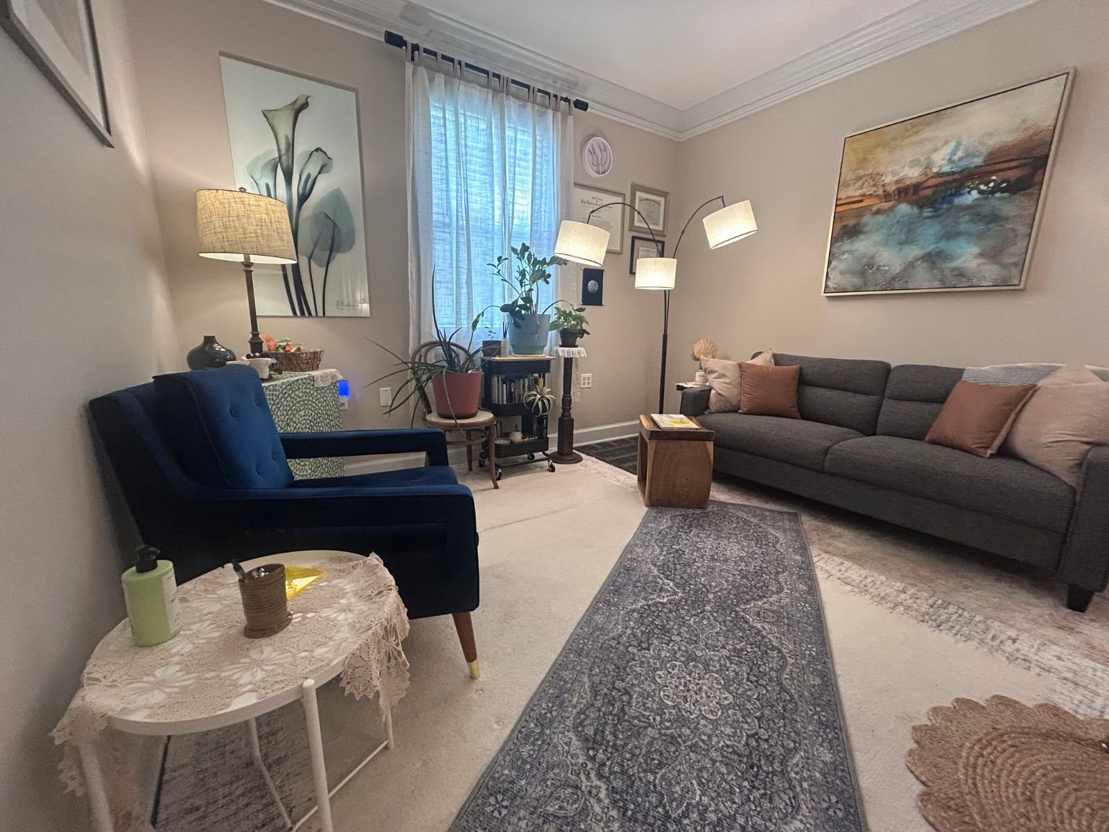 The Knoxville therapy office, with a blue armchair, a gray sofa with pillows, plants, and warm lamps